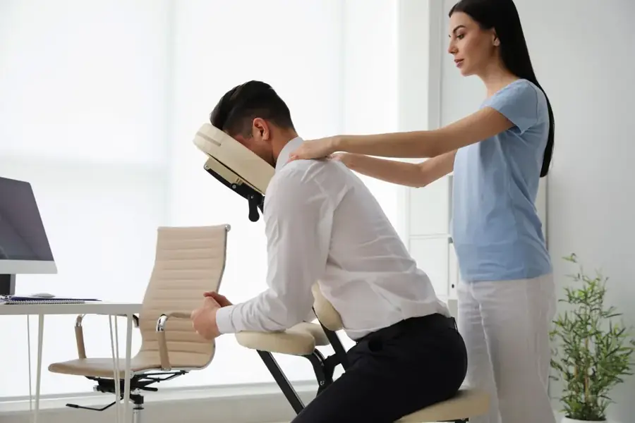 Therapist giving a chair massage to an office worker at their workplace